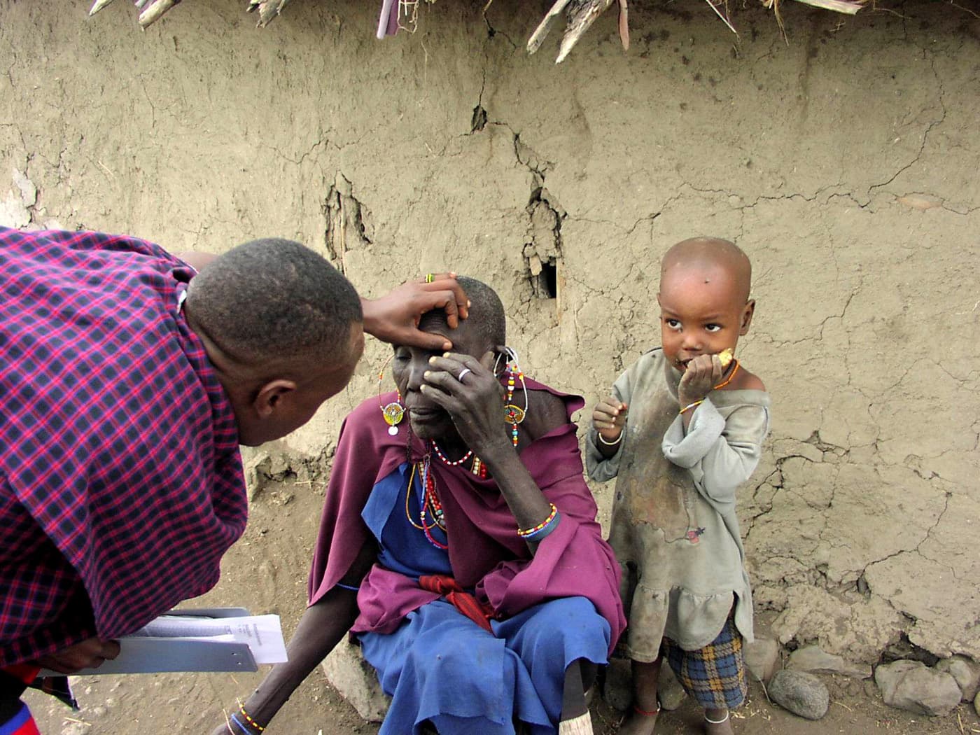 A woman receiving an eye examination while holding her child